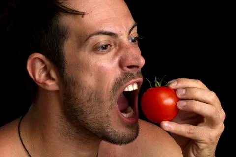 Man biting a tomato Stock Photos