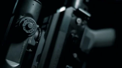 Man on a black background adjusts an optical collimator sight Stock Footage 144071075