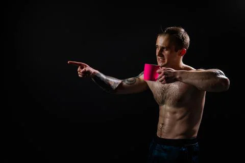 Man on black background keeps dumbbells pumped up in fitness bodybuilding sport Stock Photos