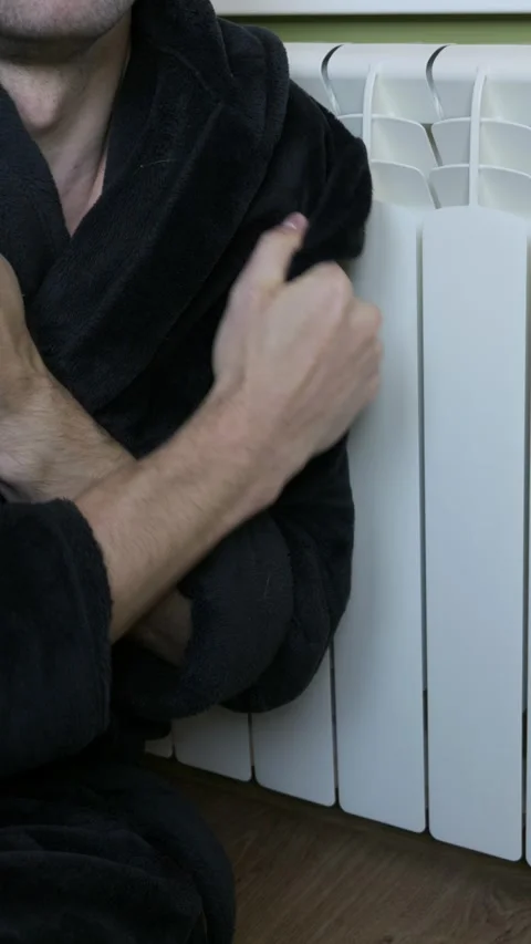 Man In Black Bathrobe Shivering And Rubbing Arms Next To White Radiator Heater Stock-Footage 328659705