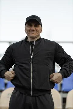 Man in a black bomber jacket and cap celebrates as he watches his favorite team Stock Photos