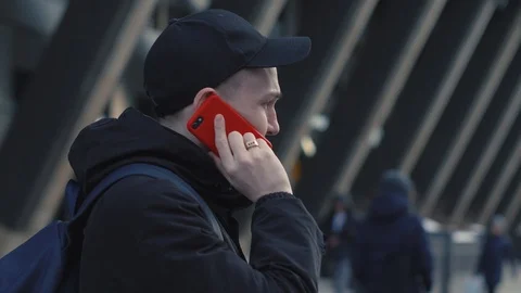 Man in black cap and jacket talking by smart phone on background cityscape Stock Footage 86533043