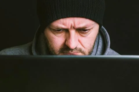 Man with black cap behind the computer monitor in the dark Stock Photos