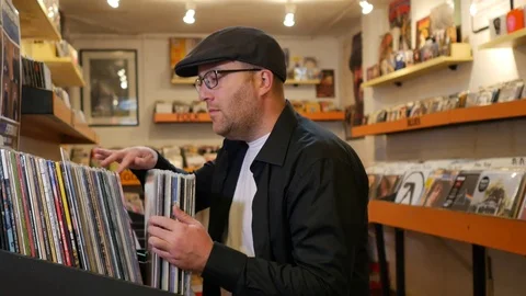 Man with black cap browsing records in the vinyl record store Stock Footage 71166570