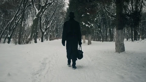 A man in a black cloak and hat walks in the park alley. 60fps. 4k 動画素材 102177519