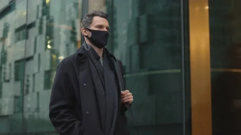 Man in black clothes wearing protective mask walking along the street Stock-Footage 144276243