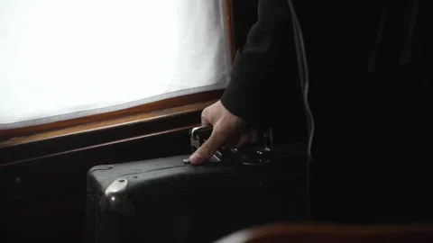 Man in black coat picks up an old suitcase Stock Footage 314761548