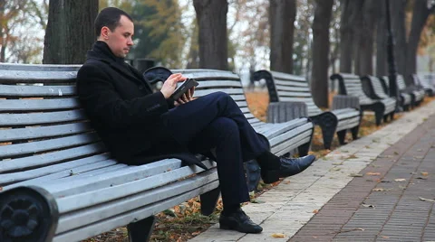 A man in a black coat with a tablet walk in the autumn park Stock Footage 45931379