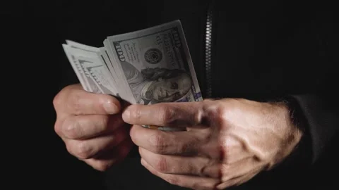Man in black counts down and hands over stack of 100 dollar bills in cash, close Stock Footage 276891989
