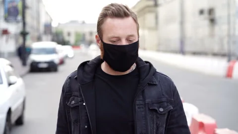 Man with black face mask walking at the street and sneezing at the elbow. Stock Footage 129542346