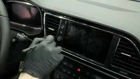 Man in black gloves cleans dashboard with brush and detergent sitting on driver 스톡 동영상 195507302