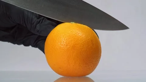 Man in black gloves slice orange fruit with big knife on a white background Stock-Footage 150772138