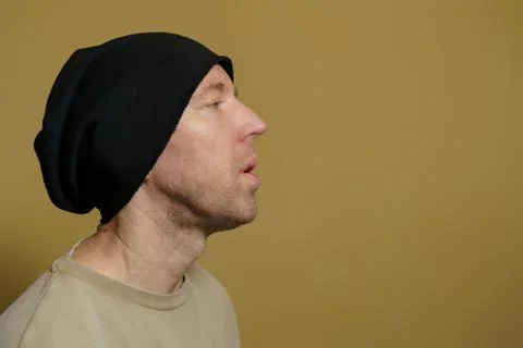 A man in a black hat lets out a cloud of smoke. Close-up portrait of a white man Stock Photos