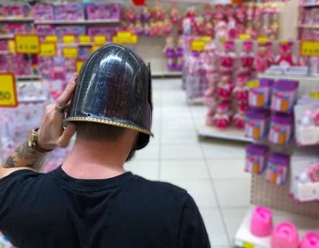 A man in black helmet standing in front of pink toys 스톡 사진