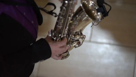 A man in a black jacket and purple shirt playing the saxophone 스톡 동영상 105015271