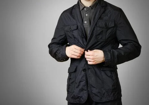 A man in a black jacket. Buttons of the hand button. Isolated on grey backg.. Fotos Stock