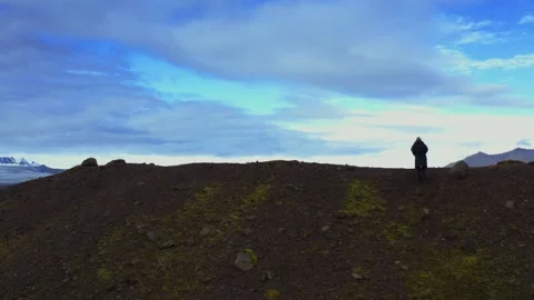 A man in black jacket climbs a rocky hill with a great view of Iceland's nature 스톡 동영상 167107528