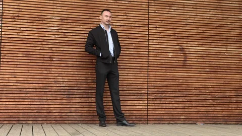 A man in a black jacket leaned on a wooden wall Stock Footage 126554208
