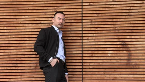 A man in a black jacket leaned on a wooden wall Stock Footage 126557682