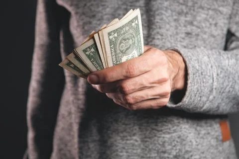 Man in a black jacket with a pack of dollar bills. Stock Photos