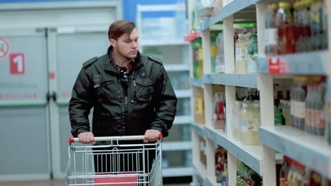 A man in a black jacket in a store takes a package of sparkling water from a Stock Footage 131341325