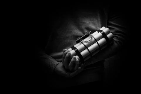 Man in a black jacket strapped with explosives and detonator holds in hand Stock Photos