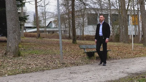 Man in a black jacket walking in the autumn park Stock Footage 126554597