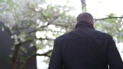 A man in a black jacket walking away in slow motion Stock Footage