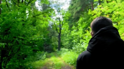 Man in a black jacket walking  in the woods on a sunny day. Footages UHD 4K 60FP Stock Footage 113277867
