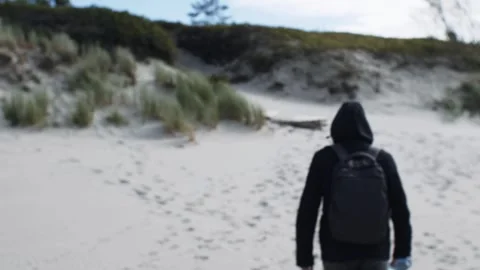 A man in a black jacket walks along the beach in gloomy autumn Stock Footage 297776254