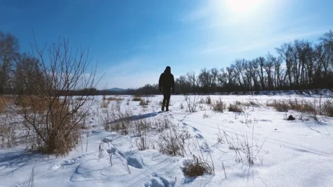 A man in a black jacket walks through a snow-covered field. Stock Footage 149500904