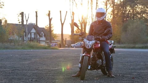 Man in black leather jacket and white helmet sits on motorcycle turns on lights Stock Footage 81493452