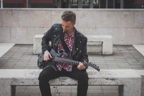 Man in black leather jacket playing electric guitar Stock Photos