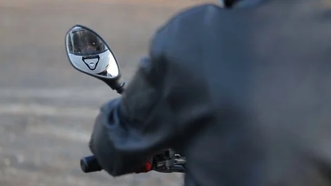 Man in black leather jacket sits on motorcycle prepares his helmet Stock Footage 81493404