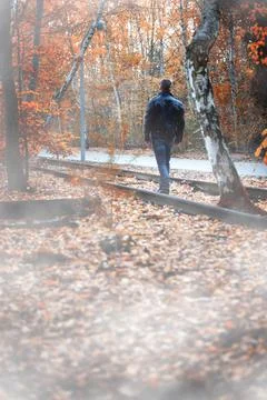 Man in black leather jacket walking on road in forest 스톡 사진