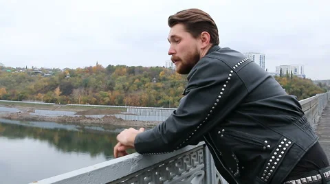 Man in black leather jackets looking at river Stock Footage 68622572