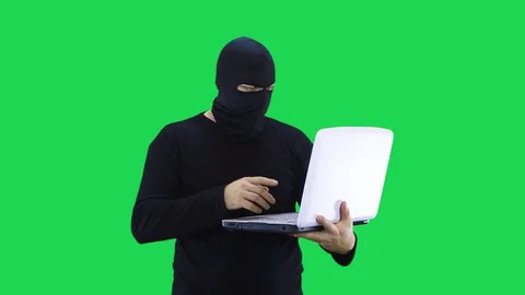 A man in a black mask talks to the interlocutor and enters data into a laptop Stock Footage 127934699