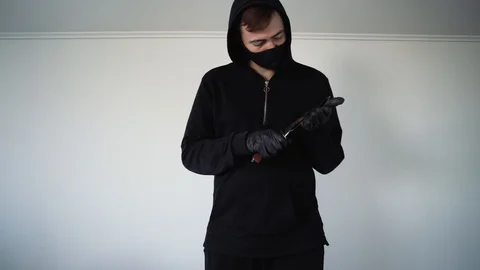A man in a black mask waves a knife in front of the camera menacingly Vidéo 129556109