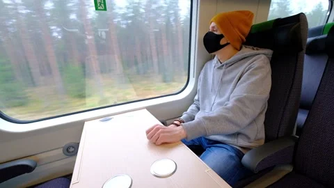 The man in a black protective mask is sitting in the train Stock Footage 142429474