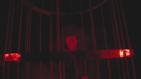 Man in black in red light in smoke near the metal cage Stock Footage 148838004