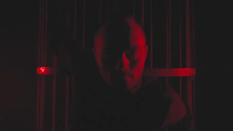 Man in black in red light in smoke near the metal cage Stock Footage 148842234