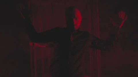 Man in black in red light in smoke near the metal cage Stock Footage 148844029
