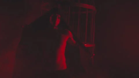 Man in black in red light in smoke near the metal cage Stock Footage 149197943
