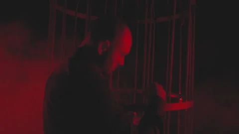 Man in black in red light in smoke near the metal cage Stock Footage 149706055
