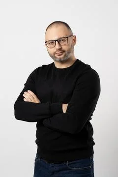 A man with black-rimmed glasses poses with his arms crossed on his chest Stock Photos