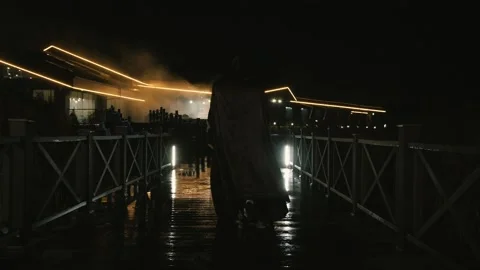 A man in a black robe det on the pier at night1 Stock-Footage 149140553