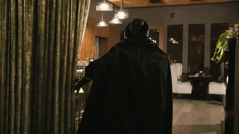 A man in a black robe opens the curtain and enters the building2 Video stock 149140682