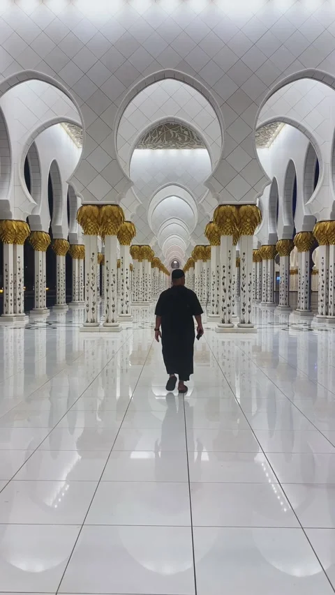 Man in black robe walking through grand white marble colonnade of Sheikh Zayed Stock Footage 340255949