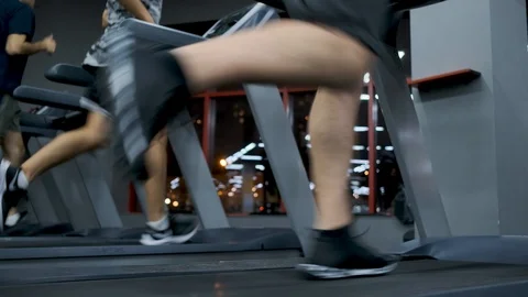 Man in black sneakers running on a treadmill against a night city background Stock Footage 123719989
