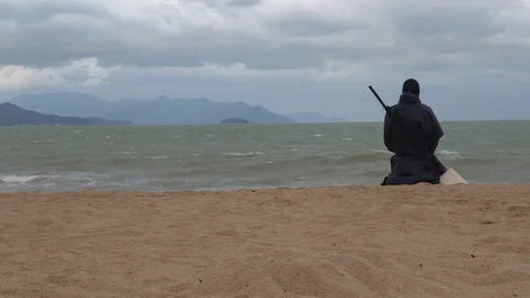 A man in black stands against the backdrop of a worrying sea and island Stock Footage 124909876